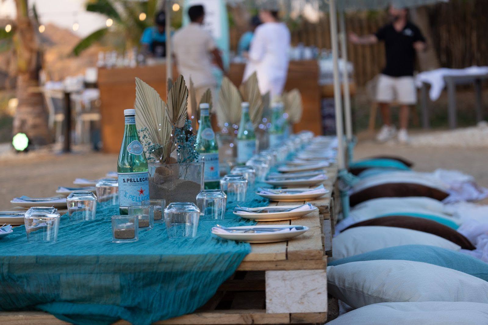 Dione beach dinner table styled with pallets, teal linens and S.Pellegrino